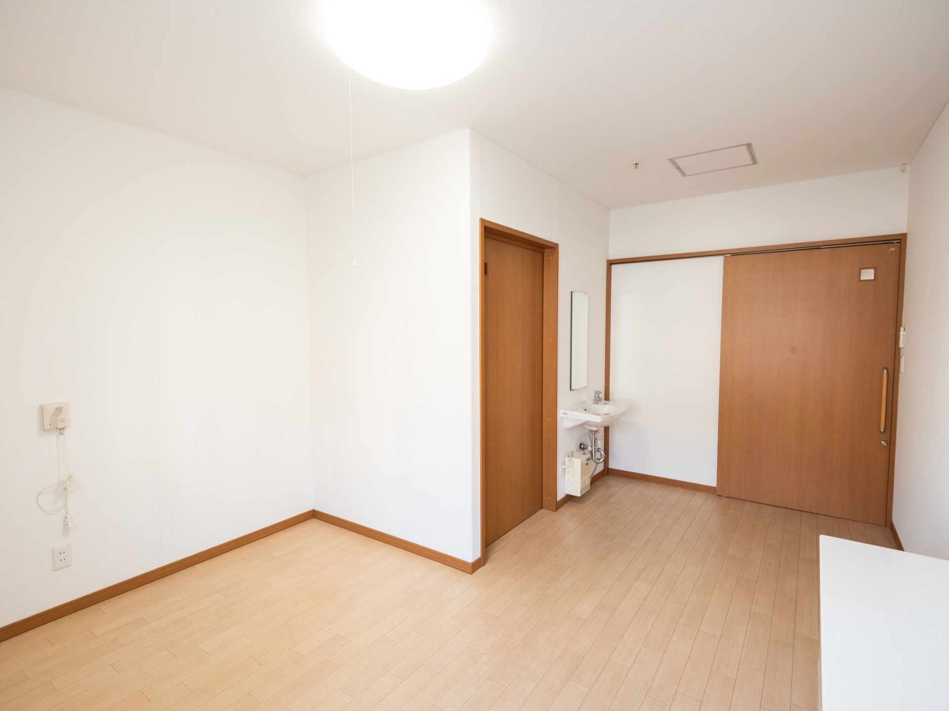 大きな引き戸式の扉を完備した、居室である。出入口付近には、コンパクトな洗面台が設置されている。縦長の鏡もある。