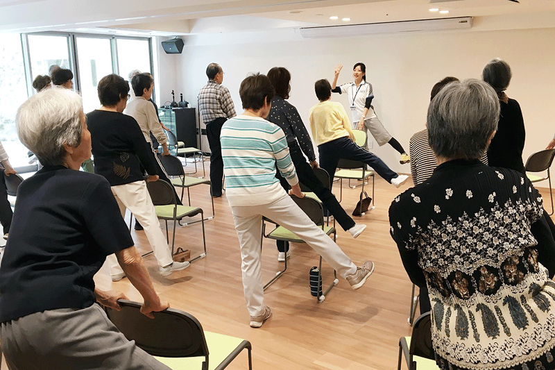 高齢者夫妻が公園を散歩している様子。後ろが豊かな自然に囲まれているのがわかる写真
