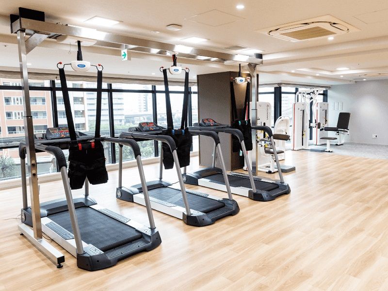 屋外でほほ笑みながら散歩を楽しむ車いすの男性入居者とエプロン姿の女性スタッフ。