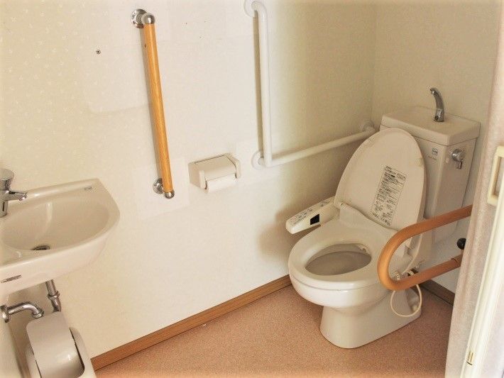 トイレの横にある壁にはアイ字型のエル字型の手すりが付き、もう片方の壁には可動式の手すりが付いている。