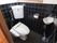 黒いタイルが床や壁に敷き詰められた個室トイレである。温水洗浄便座を取りつけ、便座横に操作パネルが設置されている。