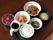 黒いトレイの上に、ご飯や味噌汁、野菜や海藻、お肉を調理したおかずの器が並べられている。飲み物とデザートの果物も用意されている。