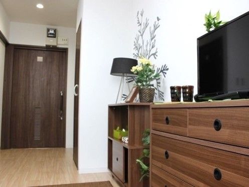 居室はシンプルなフローリングの部屋で収納棚やテレビが置かれている。