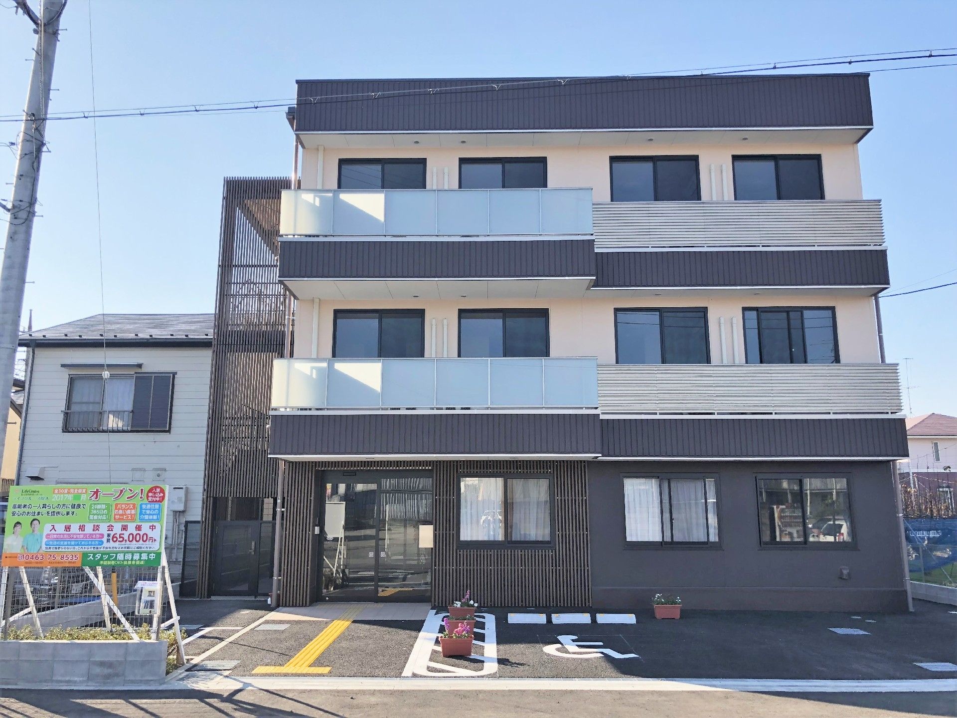 ３階建ての建物は各フロアにベランダがあり、建物の周辺には住宅が多くある。