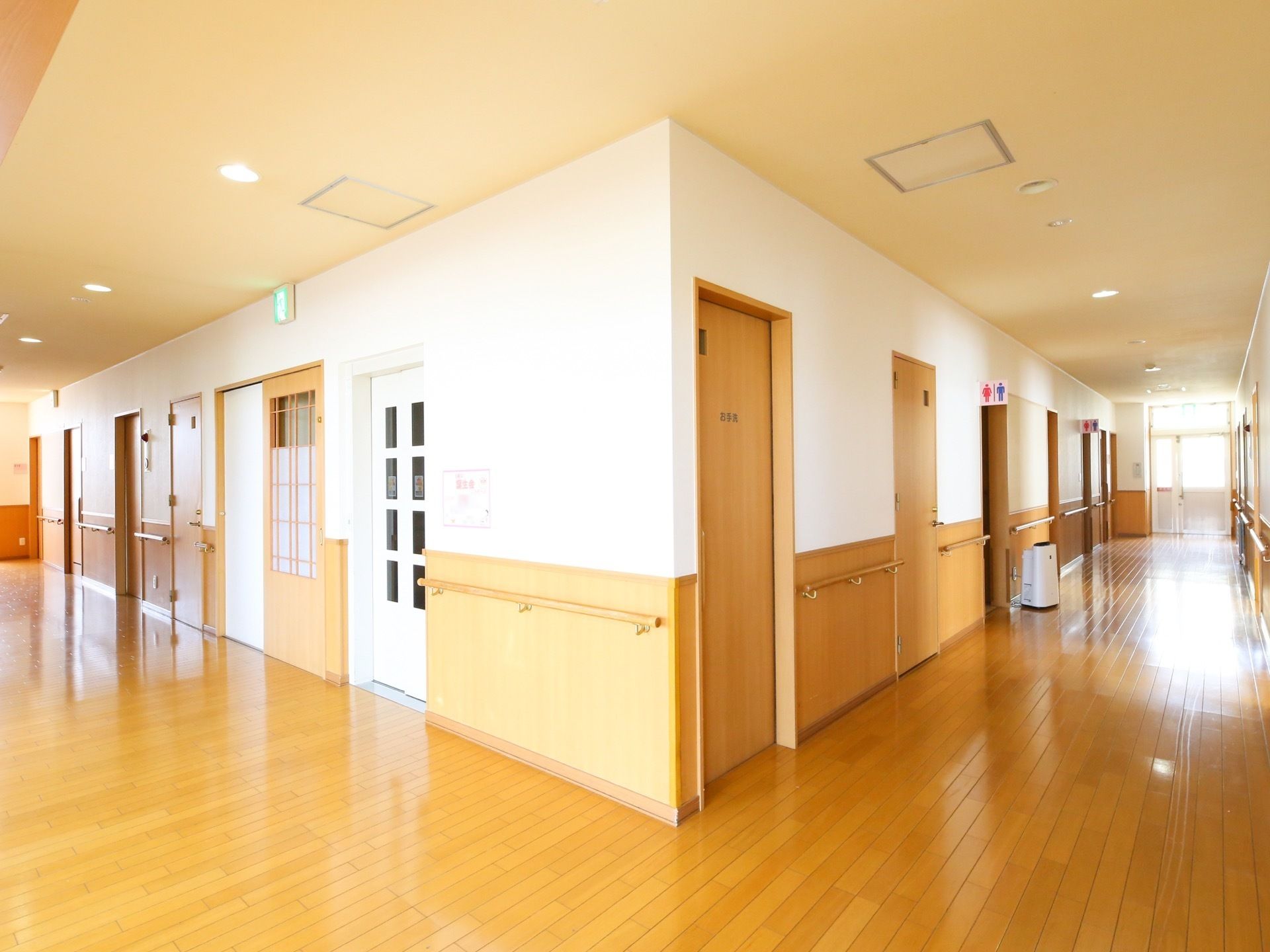 ホーム内の通路。壁には手すりが設置されていて、トイレやエレベーターなどの多数の扉が並んでいるのが見える。