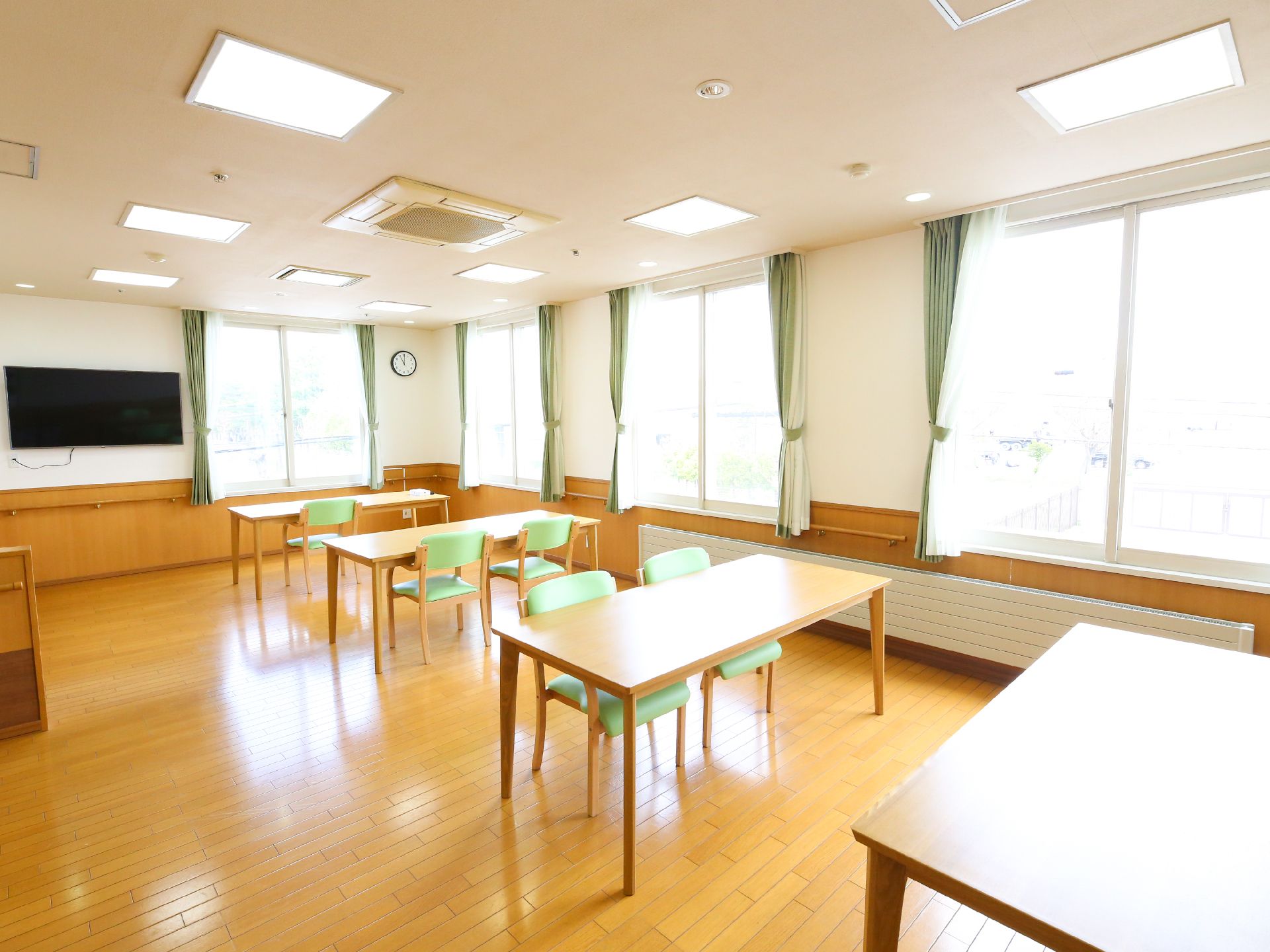 二人がけのテーブルと壁がけのテレビが設置された多目的スペース