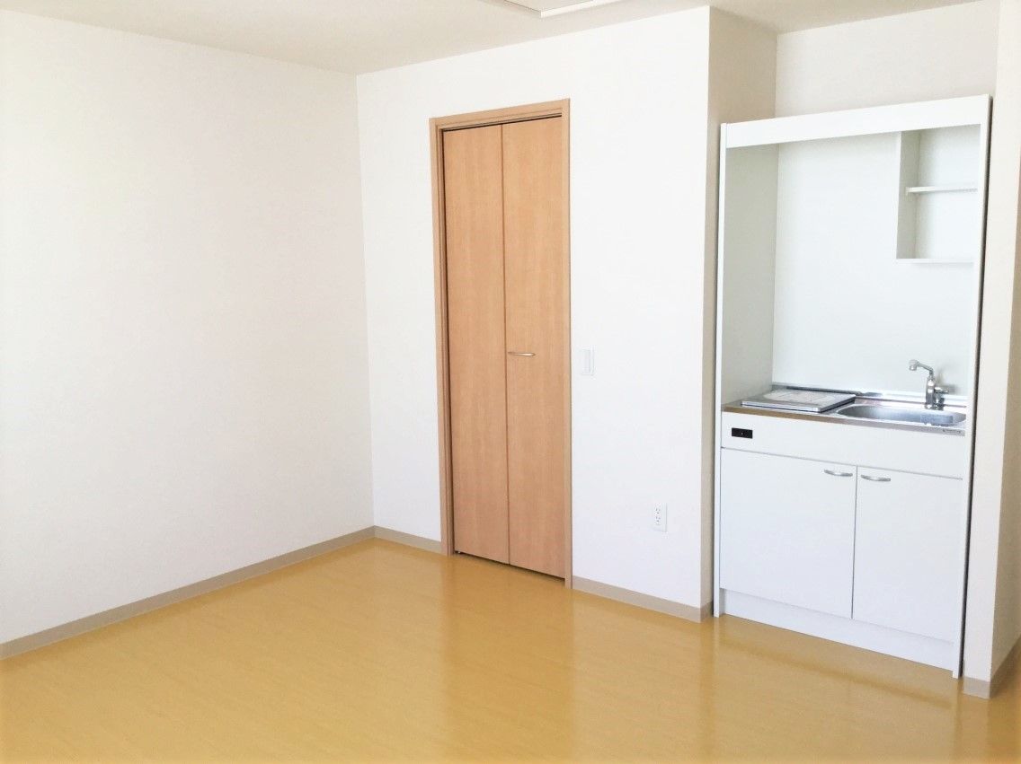 手すりが壁に取り付けてある居室の様子。収納とミニキッチンがあるワンルームの部屋