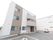 3階建てのスタイリッシュなデザインの建物の前に広々とした駐車場がある。手前には優先駐車場が設けられている。