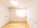 淡いピンク色のカーテンが取りつけられた窓がある。部屋の上方には、円形の大きな照明やエアコンが設置されている。