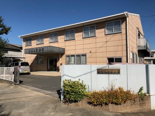 パジャマ姿でベッドに横になっている高齢女性に温かく介護に当たるエプロン姿の女性。