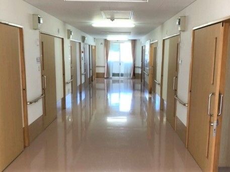車いすの男性入居者とエプロン姿の女性スタッフが外での散歩を楽しんでいる。