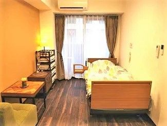 大きな窓が付いた居室はフローリングでエアコンやベッドなどが完備されている。