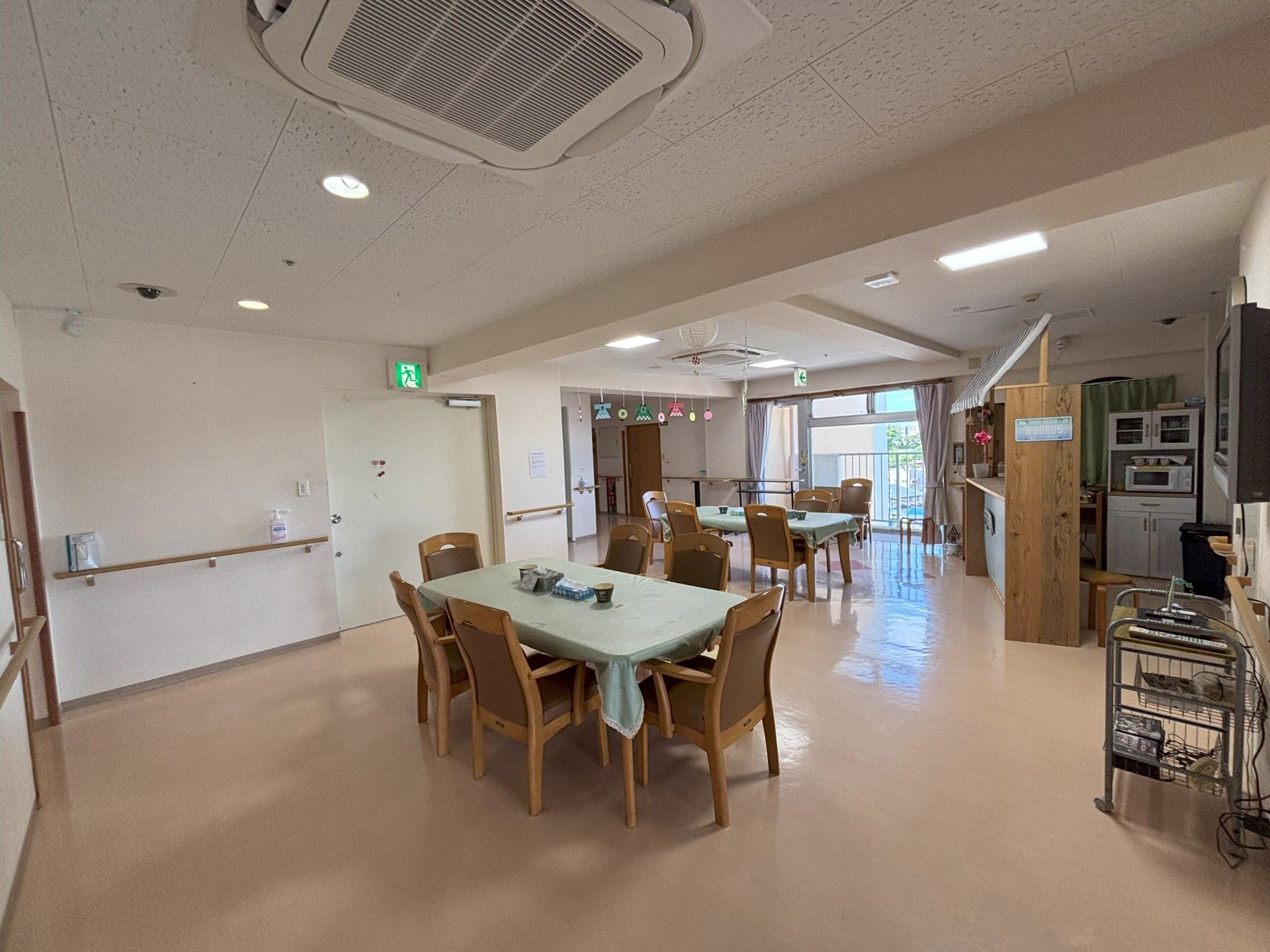 笑顔でアジサイの貼り絵をしている高齢女性とエプロンを付けた若い女性スタッフ。