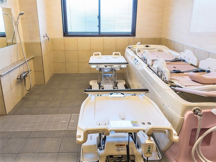 寝台浴はピンクと白で、奥には大きな窓とシャワーが付いている。