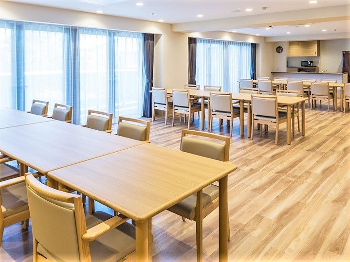 大きなダイニングテーブルが3つ置かれた食堂は、窓も大きく、奥には対面式のキッチンがある。