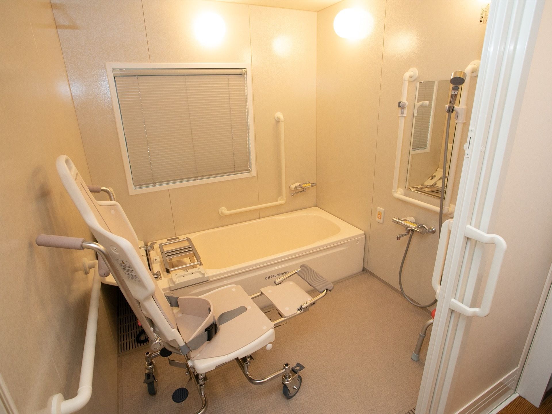 連動タイプの引き戸式を採用している。白色を基調とした浴室である。介護専用の入浴チェアが備えつけられている。