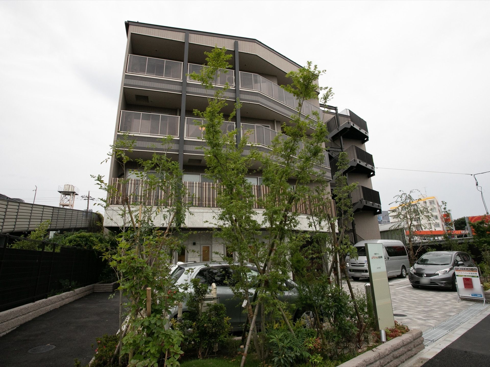 こまめに整備された緑地が設置されている。複数台の車が停められる、駐車場も完備。建物は４階建てである。