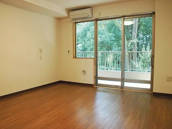 大きな窓が付いたフローリングの部屋にはエアコンがあり、壁には緊急通報装置がある。