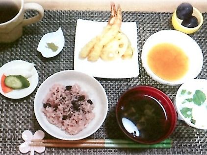 赤飯やてんぷら、吸い物にフルーツといった豪華な食事。桜の花の箸置きが使われている。