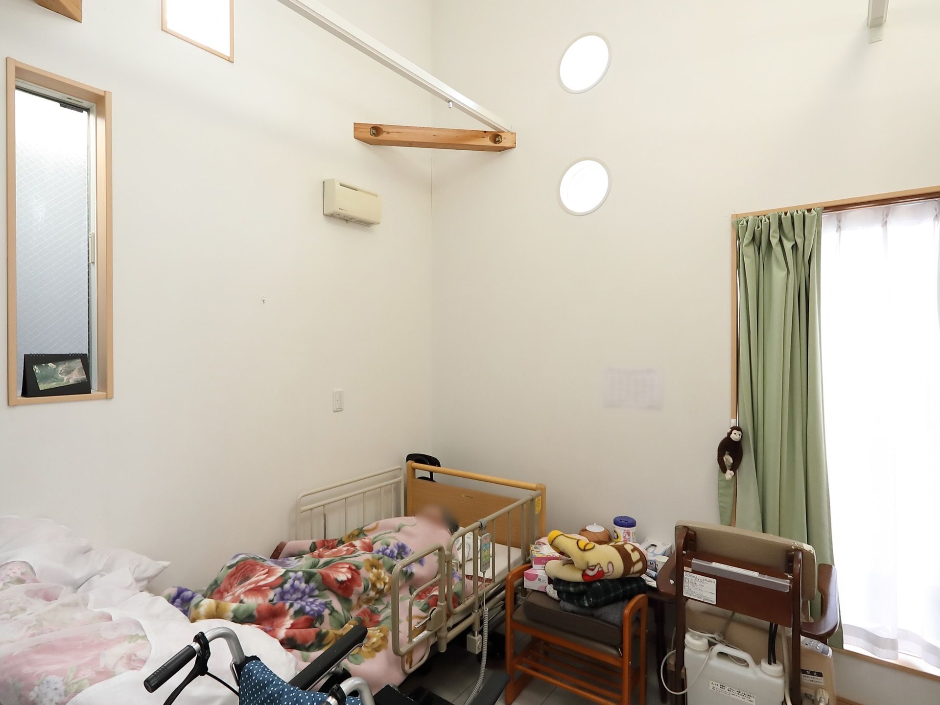 個室の部屋である。ベッドでは入居者様が睡眠を取っている。窓にはカーテンが掛けられおり、日当たりが良い。