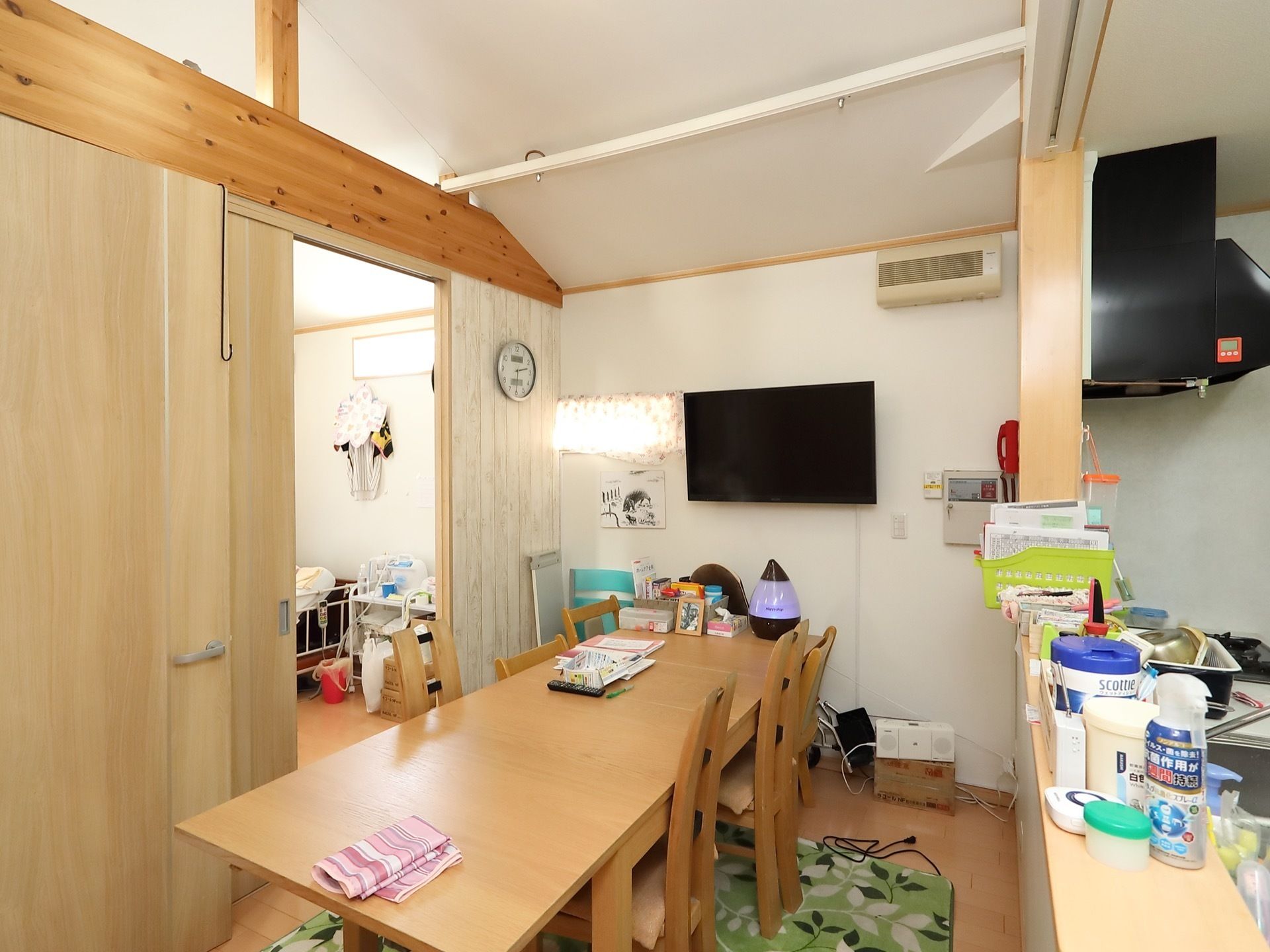 キッチンが併設されており、カウンターには小物が置かれている。床にはカーペットが敷かれており、ダイニングテーブルが用意されている。