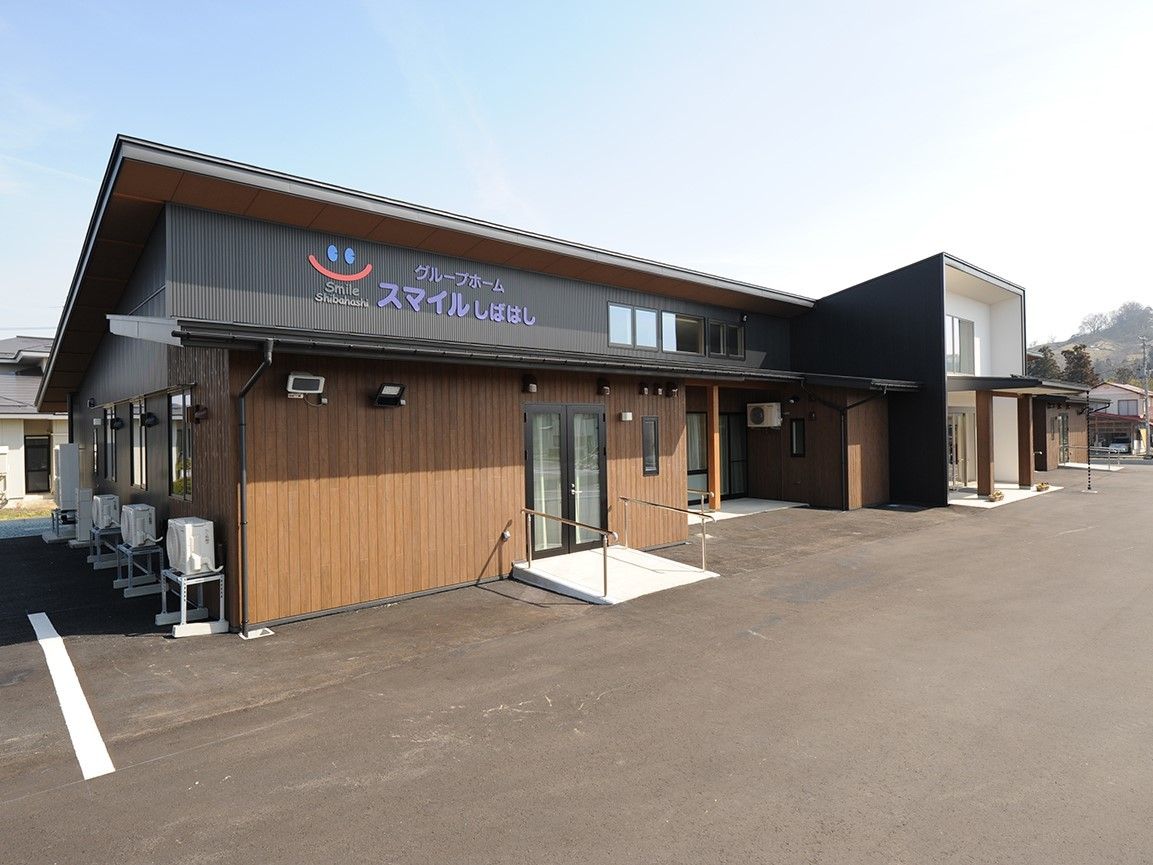 ブラウンと黒の平屋建ての建物。敷地は広く、駐車スペースもある。
