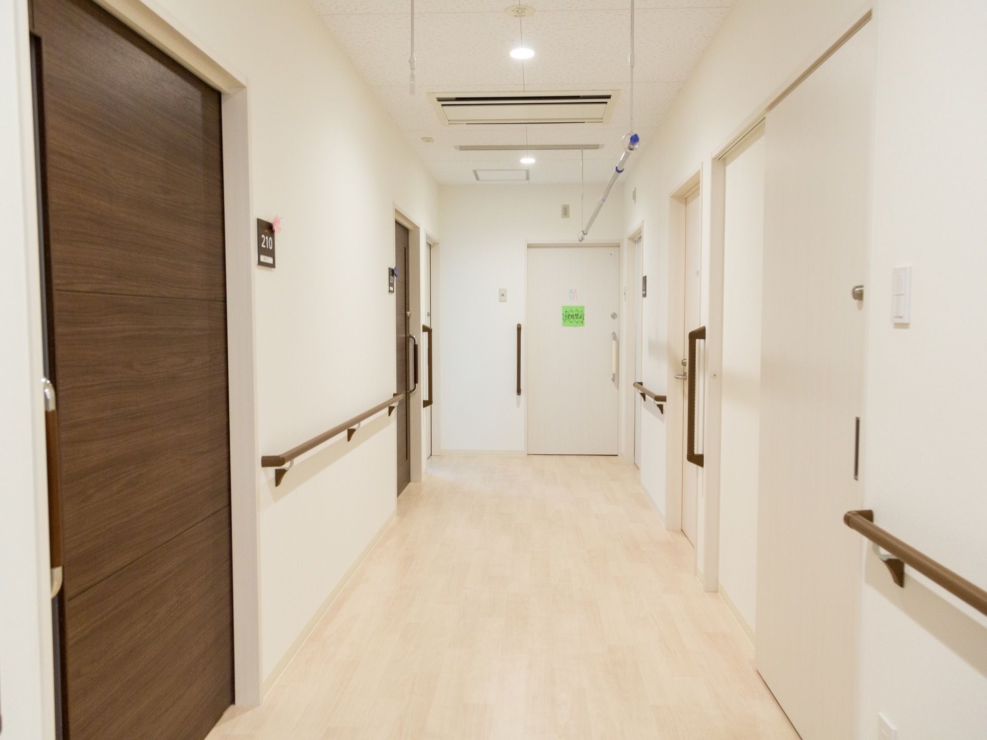 廊下の天井から下がった棒に、物干し竿を設置している。部屋番号のプレートは、白い文字ではっきりと書かれている。