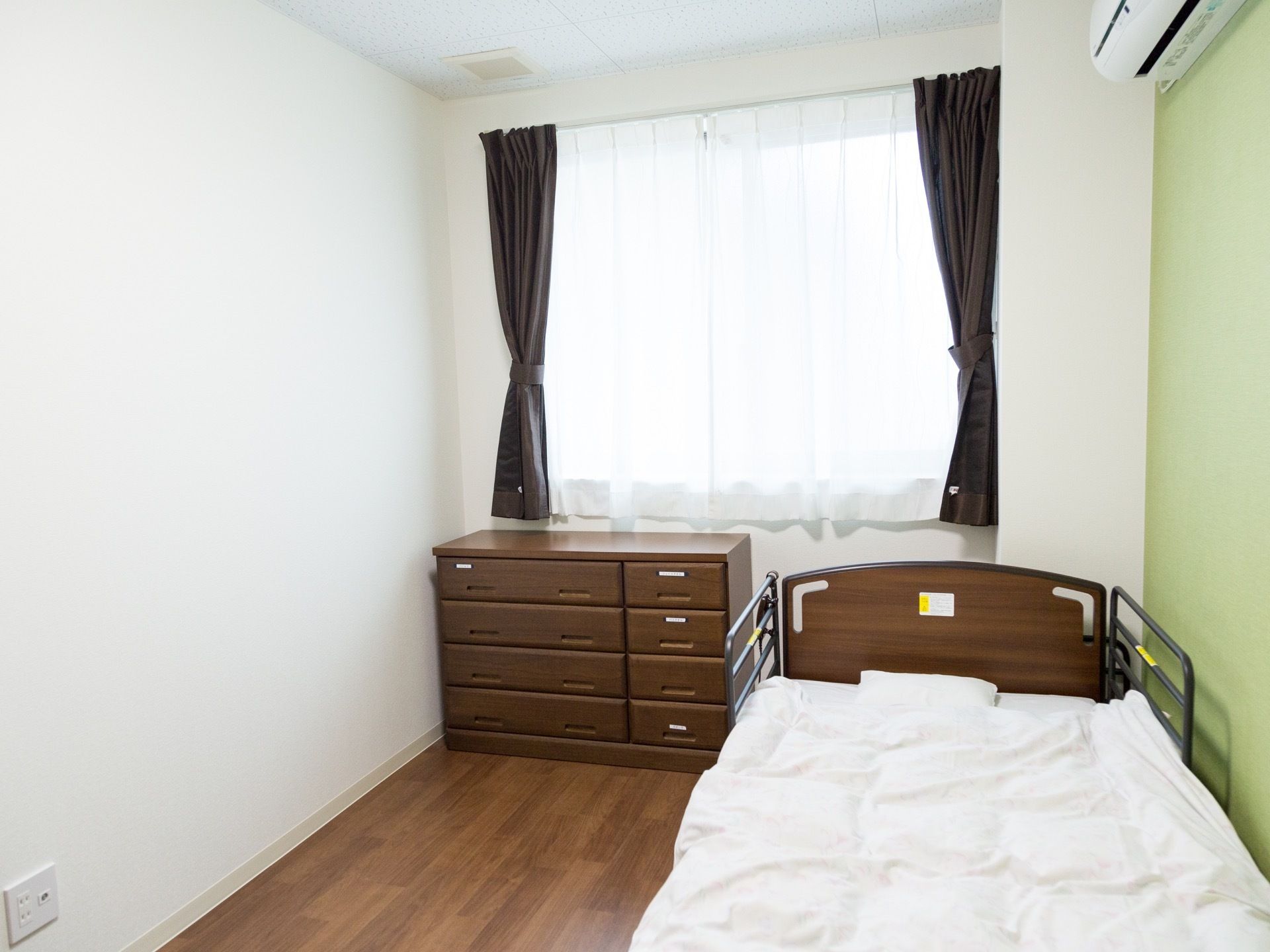 お部屋のフローリングには木目が見える素材を使っている。ベッドとキャビネットは、同系色のダークブラウンである。