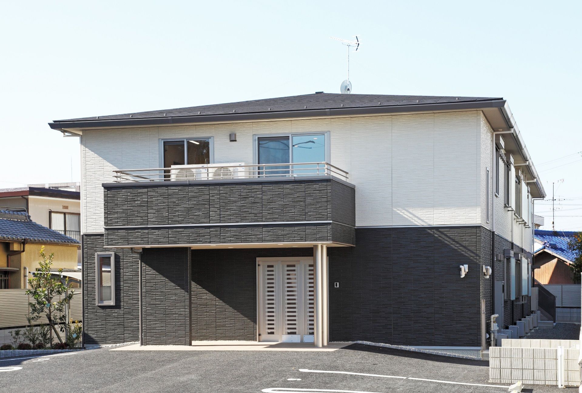 2階建ての建物。1階部分はダークグレー、2階部分は白で、三角屋根が付いている。