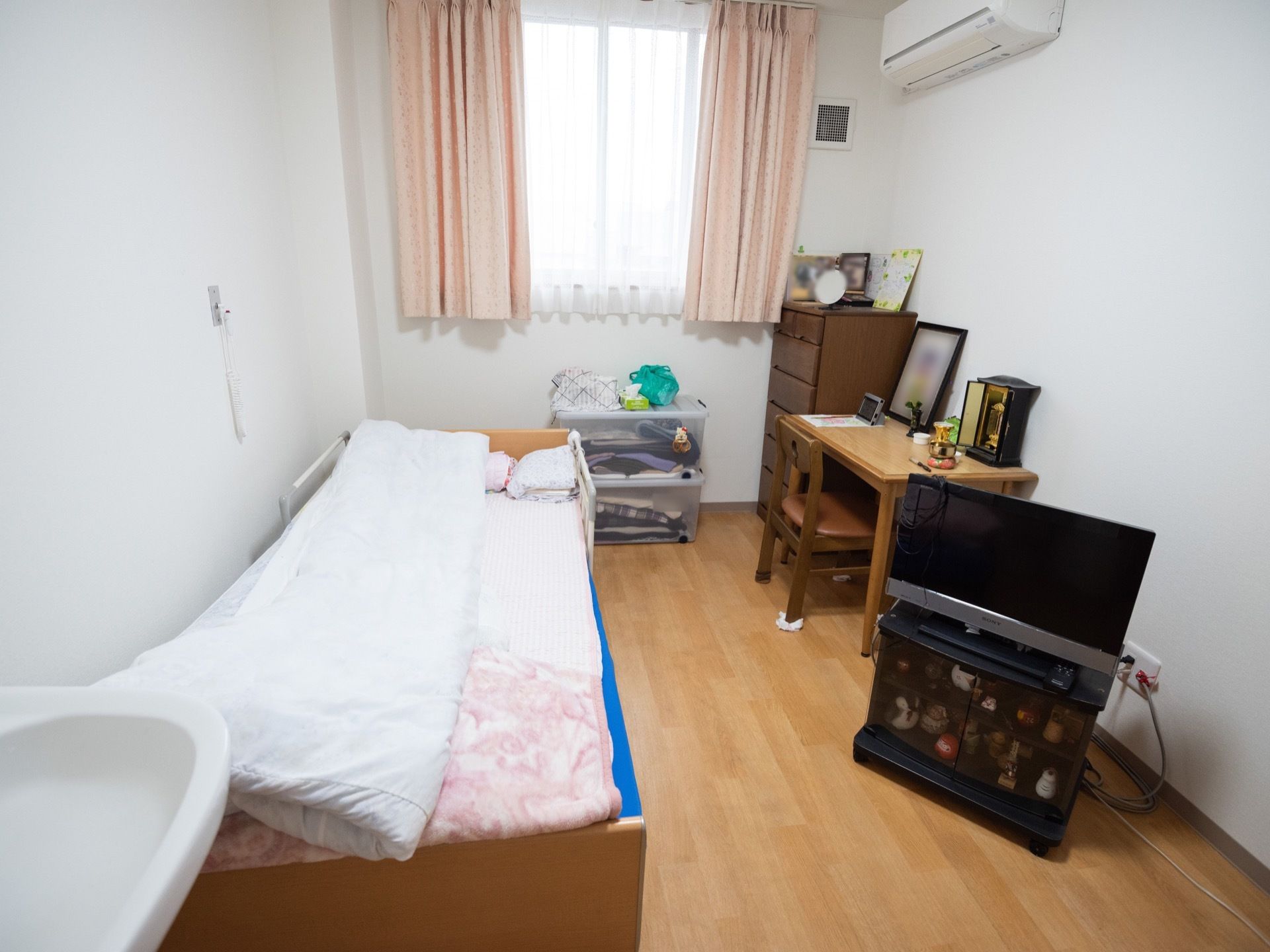 出窓があり、介護用ベッド、エアコン、テレビが設備されている居住空間