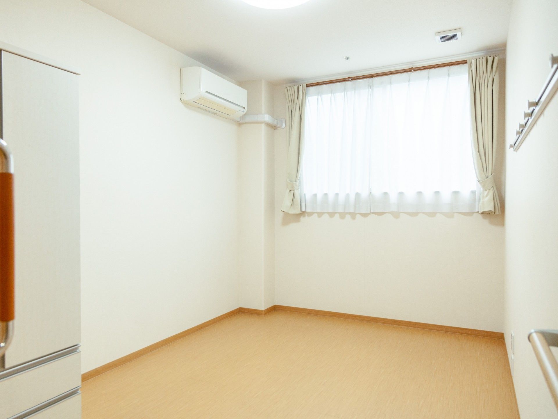 車椅子に乗って手を振る高齢女性と後ろで介助をする男性介護士