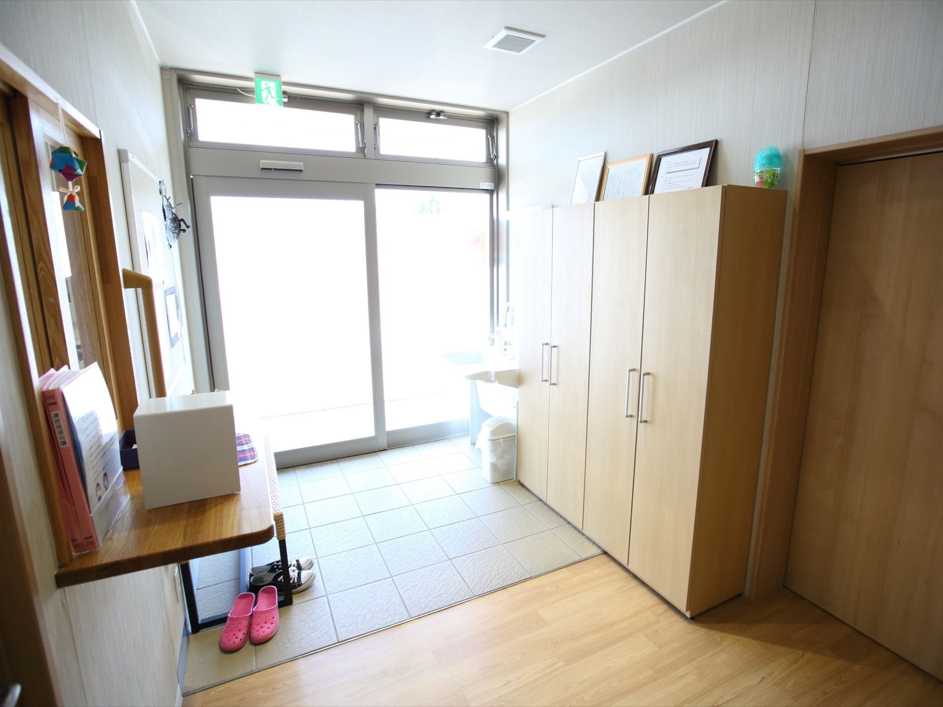 大きな自動扉が設置された玄関。土間と廊下は段差のないバリアフリー設計である。受付カウンターがあり、反対側に下駄箱収納が備え付けられている。