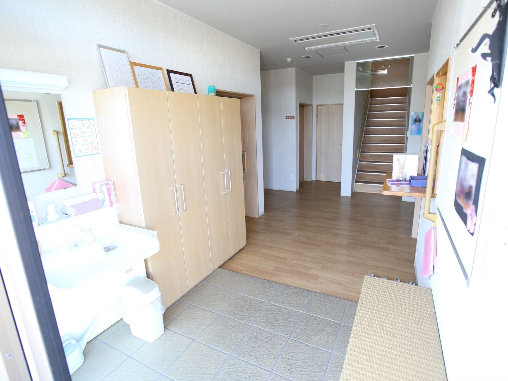 きれいに整えられた玄関である。左手に洗面設備、右手にはベンチが置かれている。土間と廊下はバリアフリー設計になっている。