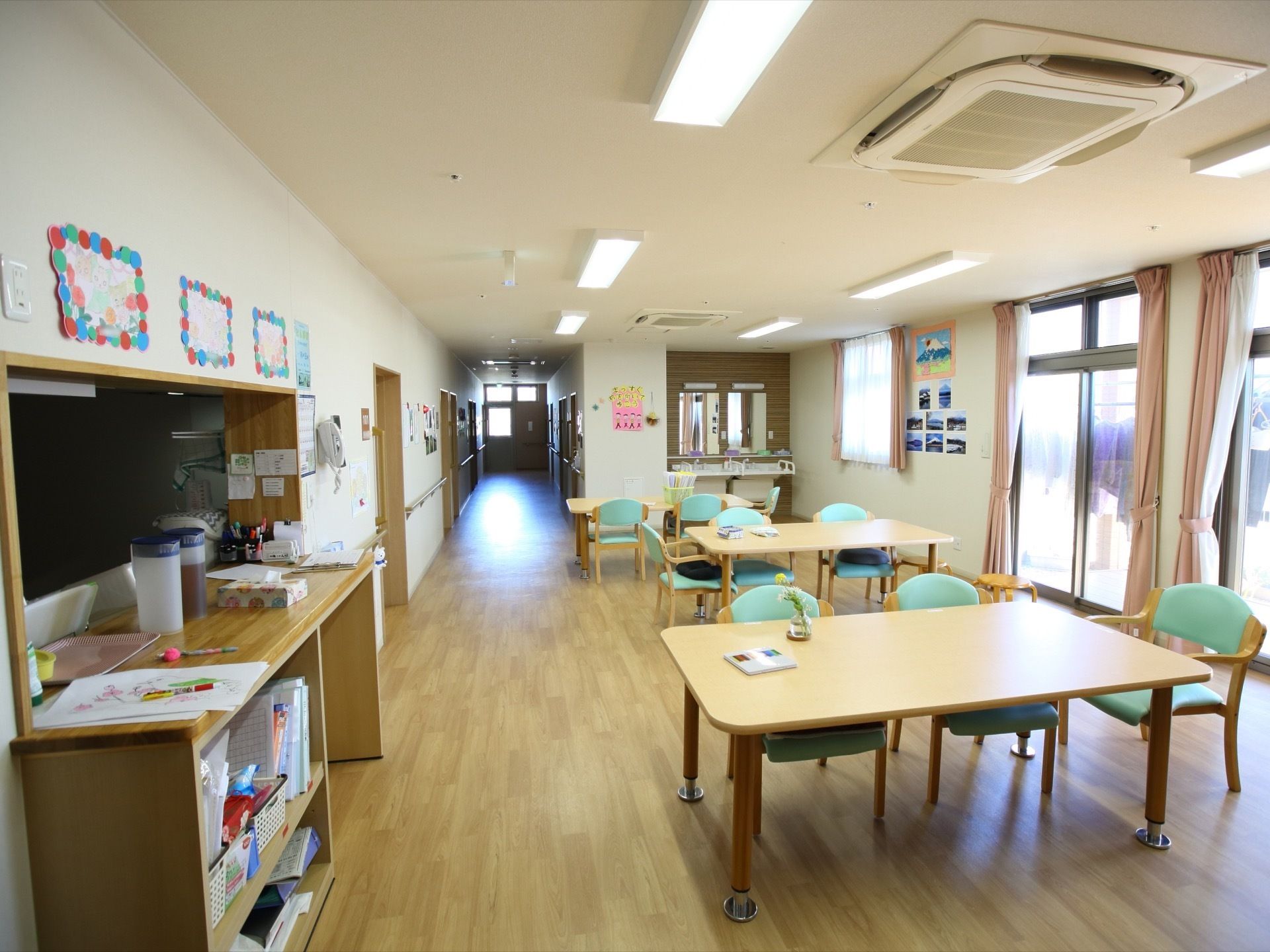 廊下とつながる食堂は、掃き出し窓が設置され、明るい空間である。テーブルと椅子が配置され、カウンターの奥は厨房となっている。
