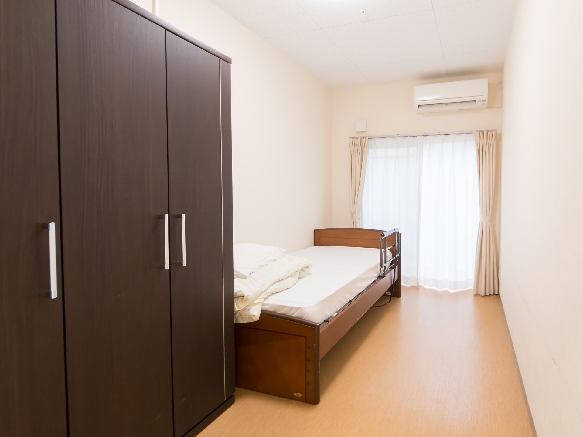 居室の奥にある窓から日が差し込み、部屋全体が明るく過ごしやすい雰囲気。家具を片側に寄せて配置し、通路を広く空けてある。