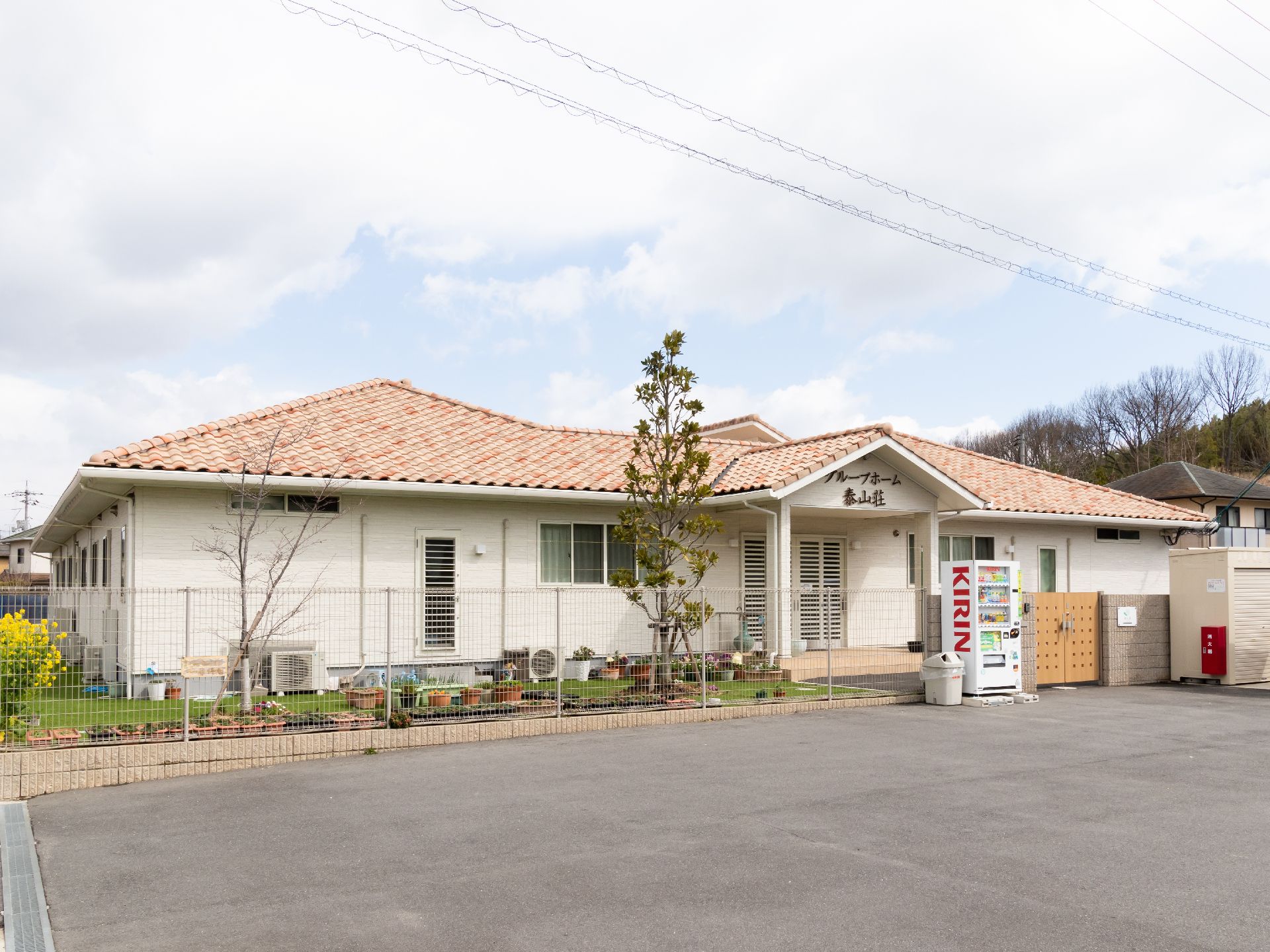 平屋建てのグループホーム。建物前に芝生の庭や花壇がある。