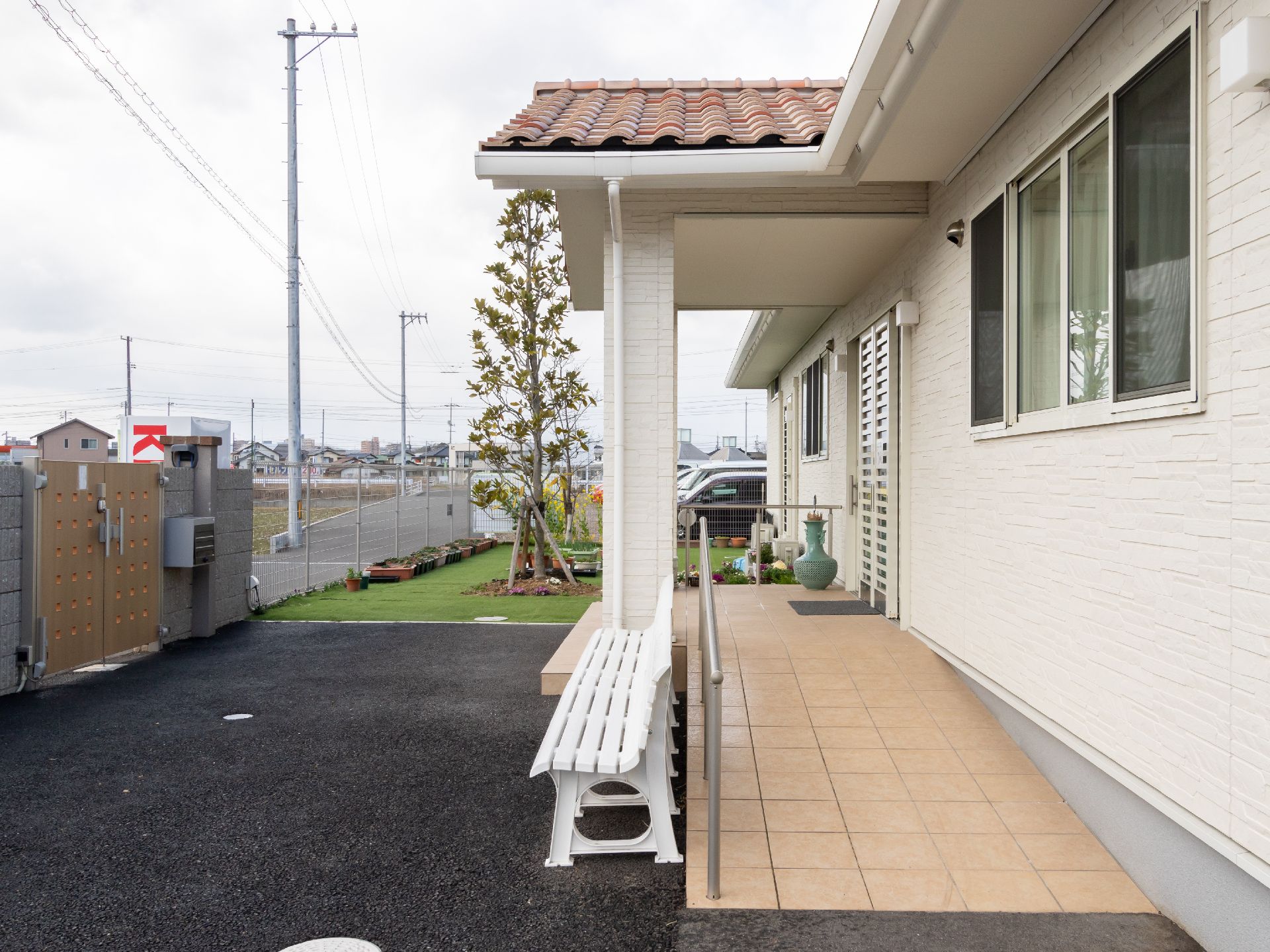 奥には芝生の庭があり、瓦屋根の建物でスロープには手すりがある外観