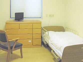 ベッド、タンス、いすなどが置いてある施設内の個室の様子
