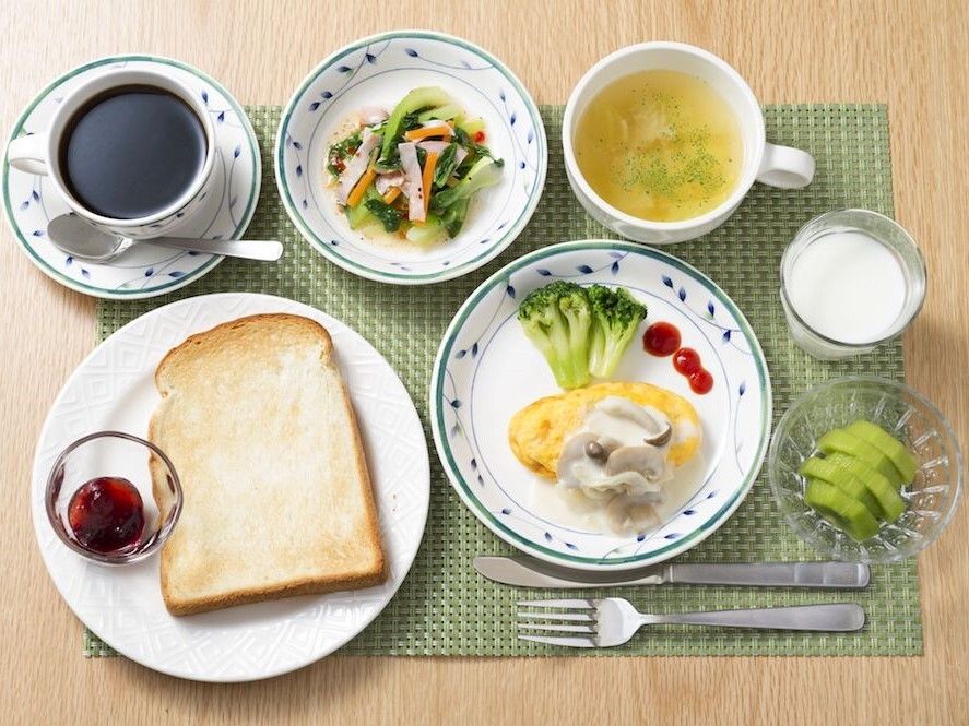 ランチョンマットの上に洋風の朝食が並んでいる。ジャムが添えられたトーストや野菜の和え物、スープにヨーグルト、フルーツなど。