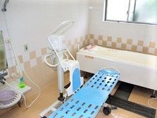 寝たまま入浴できる寝台浴が設置された浴室はタイル張り。大きな窓が付き明るい雰囲気。
