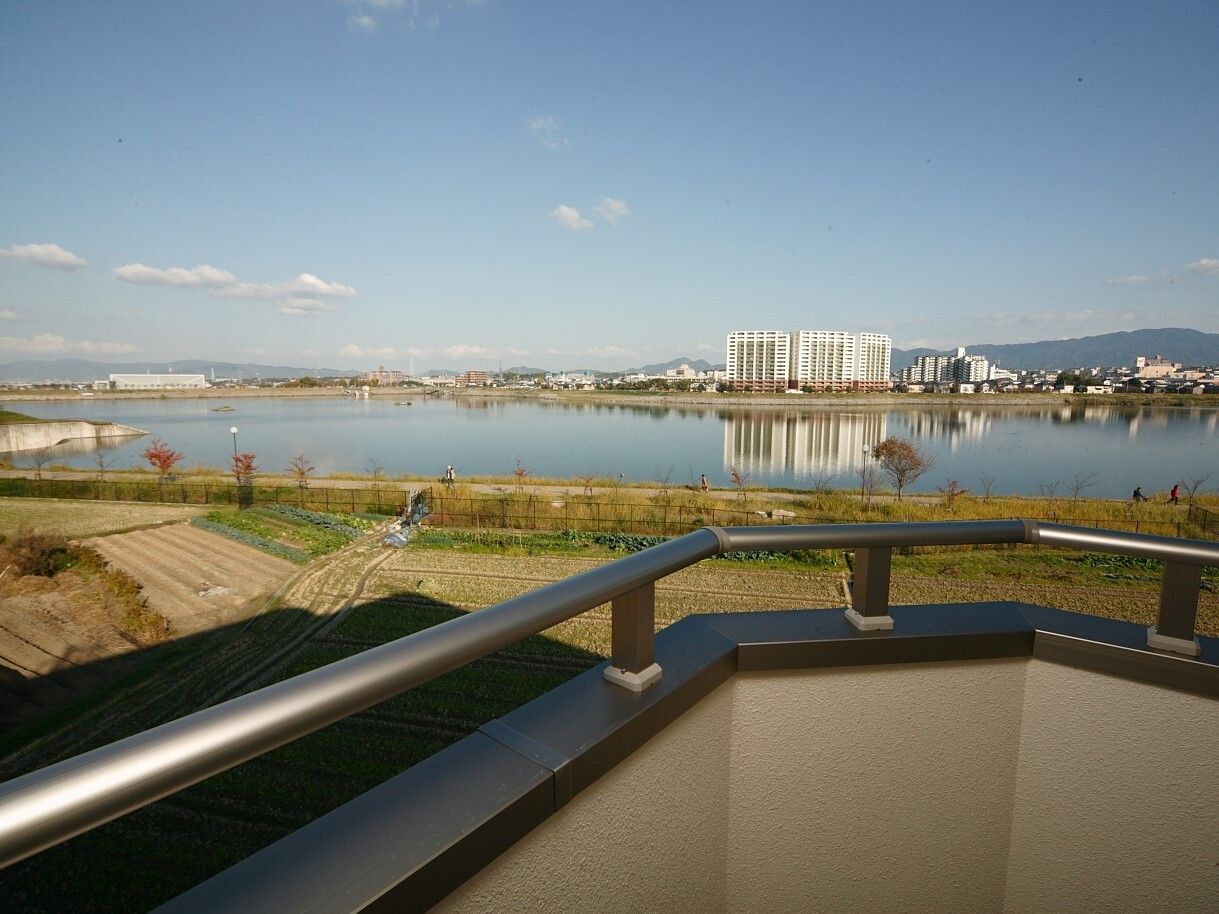ホームのバルコニーから見渡すことができる自然あふれる風景。すぐそばには広い川が流れ、その奥には街が見える。