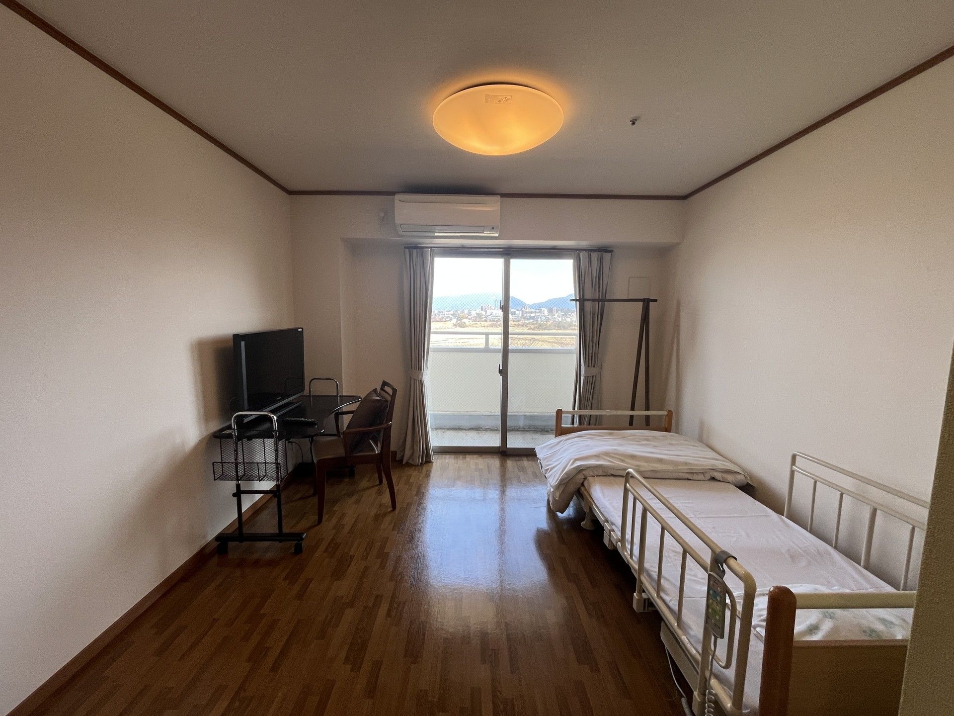 窓際のベッドと机の部屋