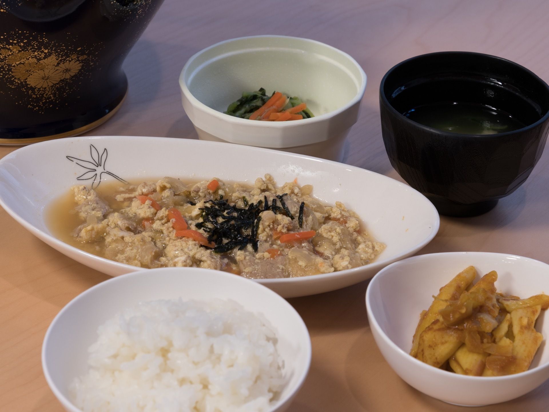 白米、味噌汁、青菜のおひたし、煮物の入った小鉢、刻み海苔のかかった親子煮がテーブルの上に並んでいる。