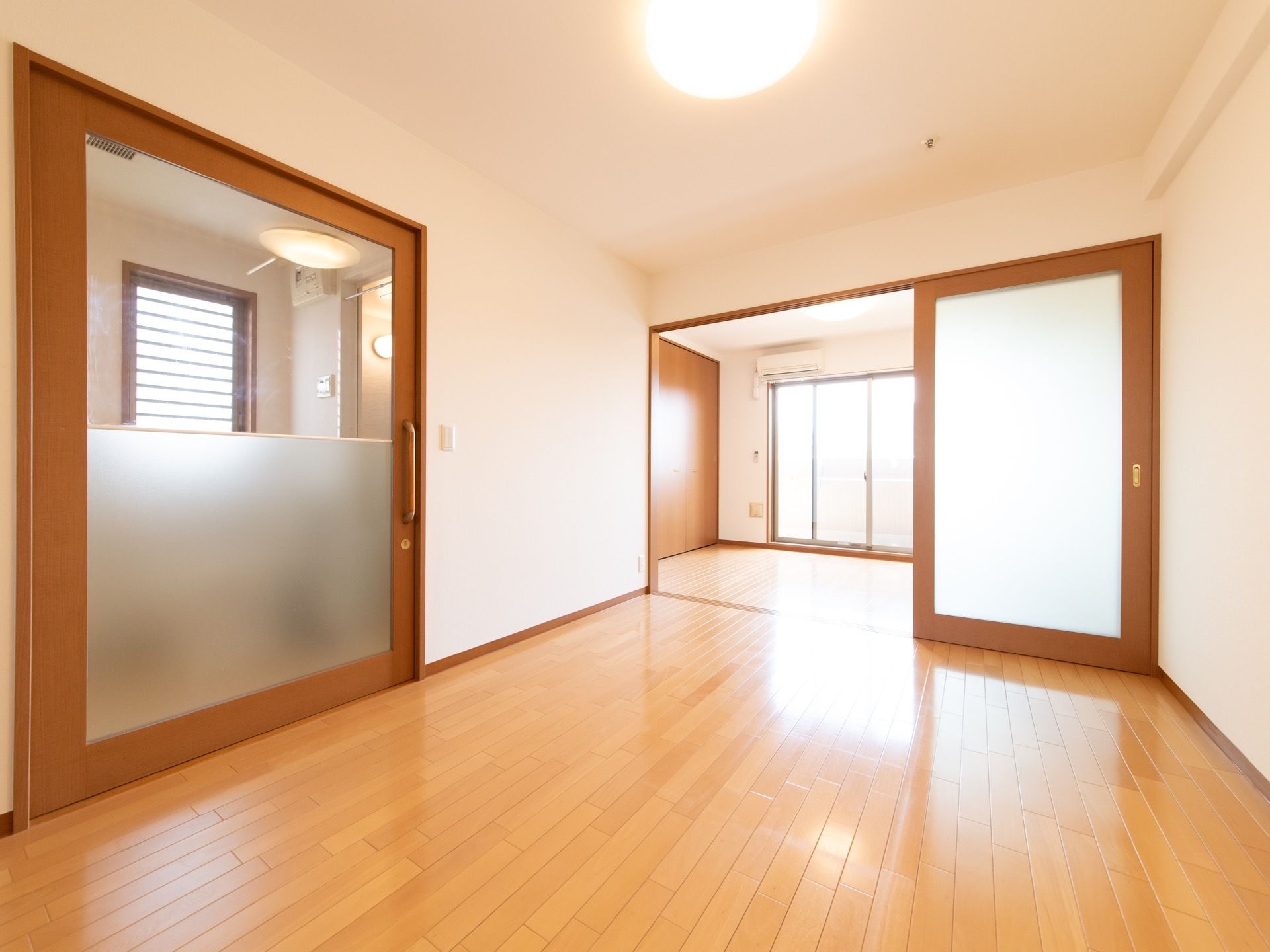 居室は洋室が２つ縦に長く続いている。広いフローリングで、真ん中にはスライド式のガラスの仕切り戸がある。