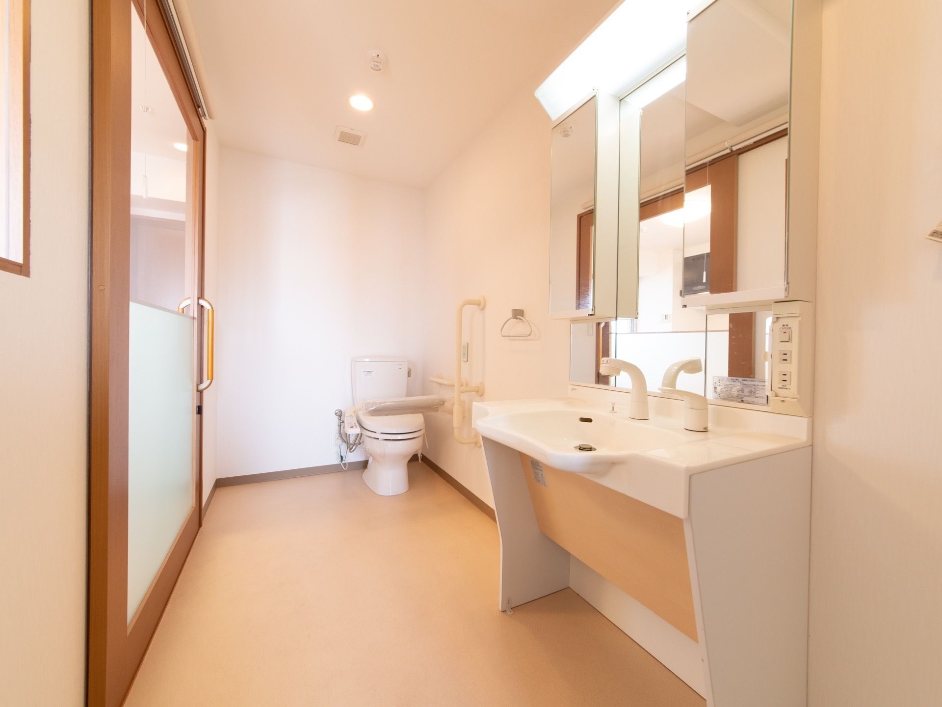 居室の中にはトイレがあり、その隣りには洗面台がある。トイレの便座の近くには手すりが設置されている。タオル掛けもついている。