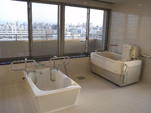 介護入浴機器と手すりが備え付けられている一般浴槽が設置された浴室