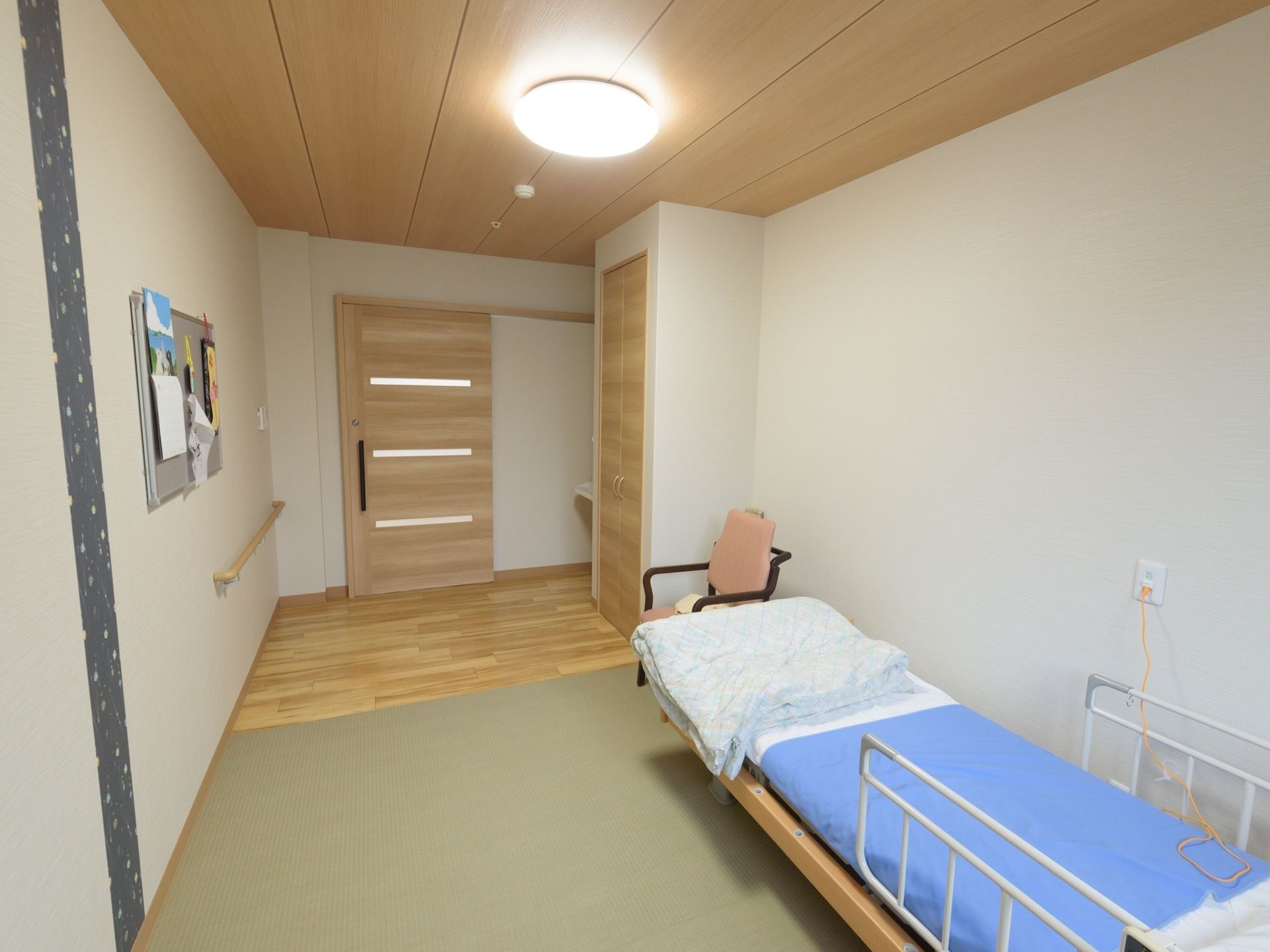 居室には介護用ベッド、クローゼット、洗面台が備え付けてある。居室内の壁に手すりがかかっている。