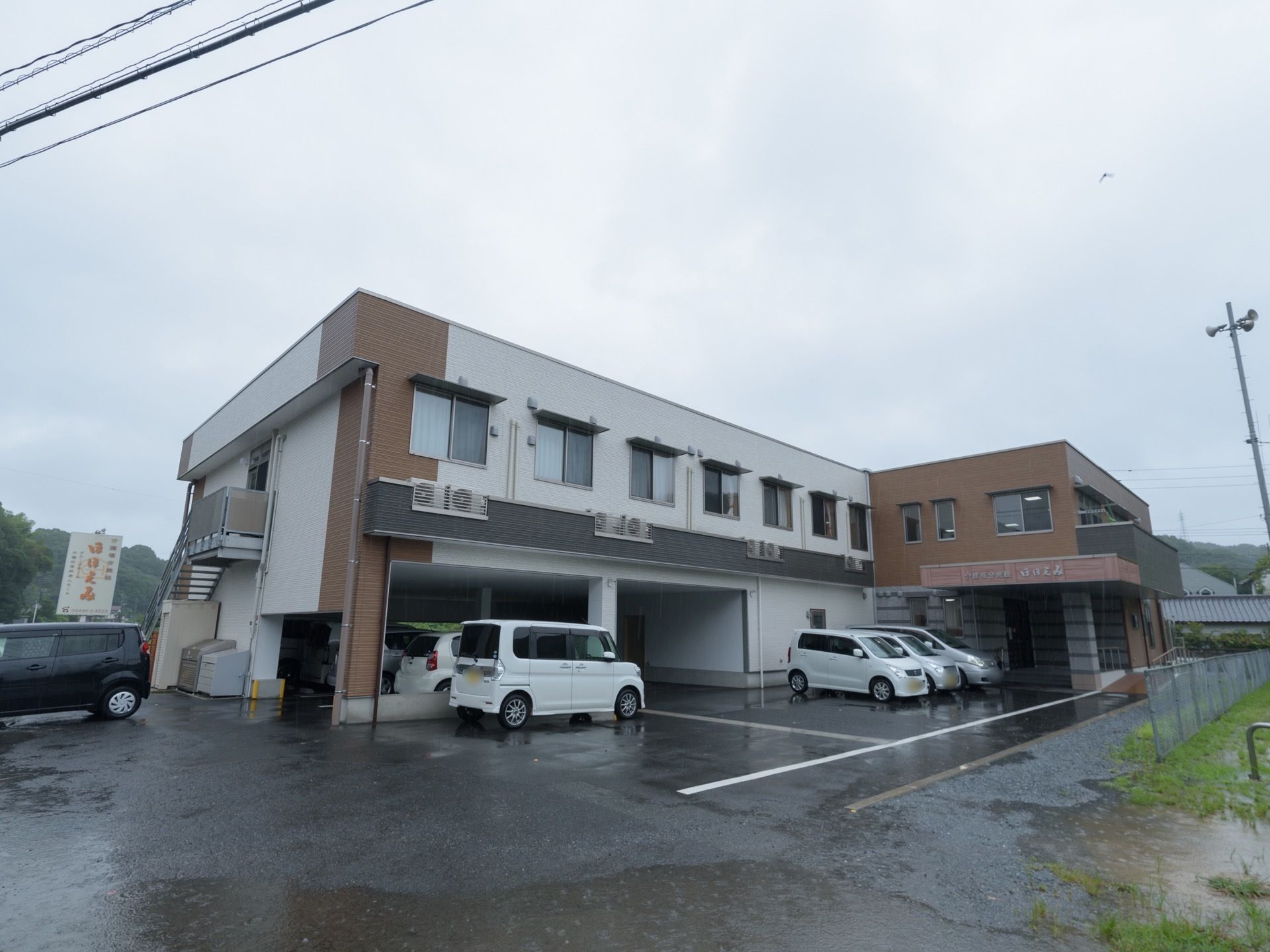 施設は２階建てで、外階段が付いている。建物前と１階部分の一部が駐車スペースとなっている。玄関にはポーチがある。