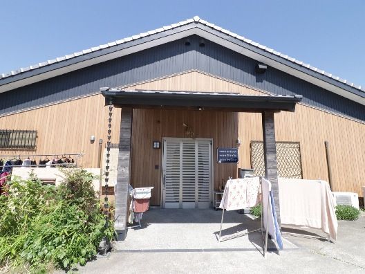 三角屋根が付いた平屋建ての建物は日当たりのいい場所に建っている。建物の玄関には布団が干されている。