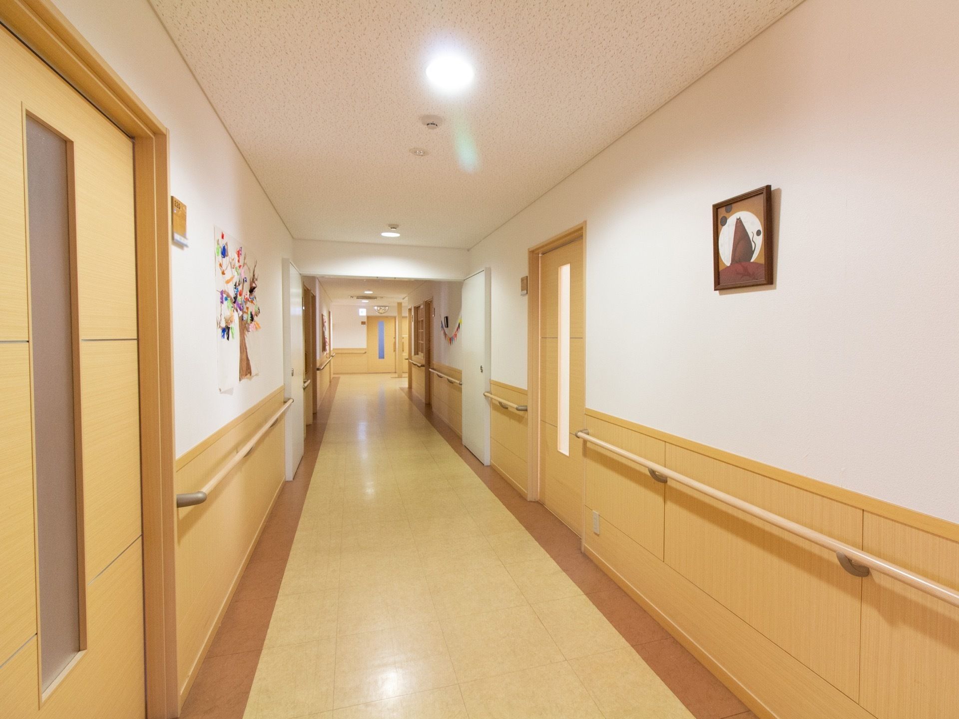 通路の両側には手すりが設置され、壁には絵画や作品などが飾られている。居室ドアは引き戸式になっている。